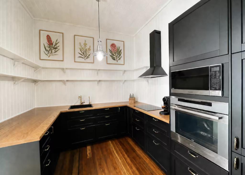 Kitchen — black cabinetry, timber benchtops and botanical prints, Little Anchorage
